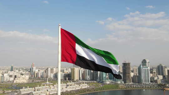 无人机视图：阿联酋北部沙迦国旗岛上空挥舞的阿拉伯联合酋长国国旗