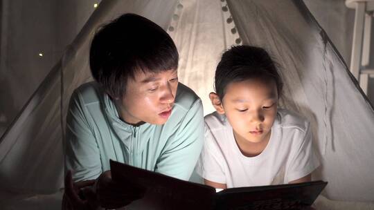 夜晚趴在帐篷里读书的母女
