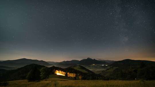 群山星空中的星星和月光下雾蒙蒙的乡村景观