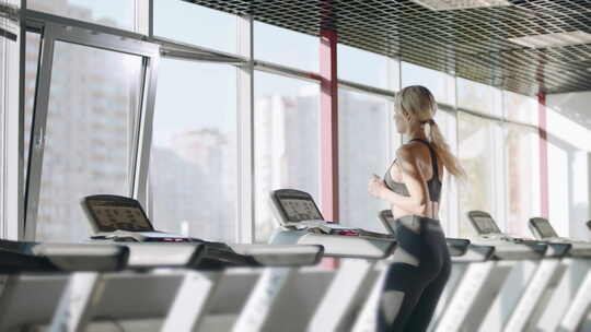 健身女性在健身俱乐部的跑步机上训练有氧运
