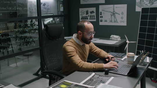 男性清洁能源专家晚上在办公室用笔记本电脑