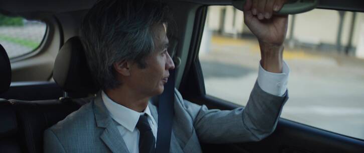 日本商人在行驶的汽车上看手机短信
