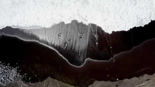 泡沫海浪冲刷着亚速尔群岛的黑色沙滩，俯瞰。