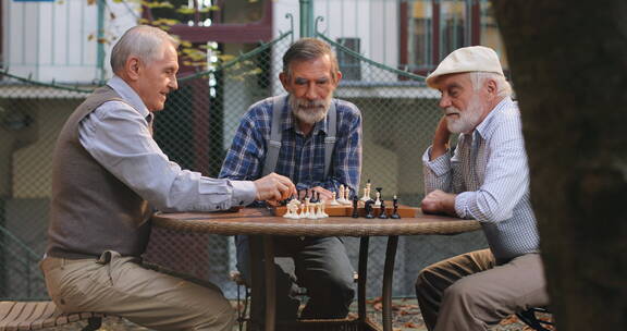 退休老人围着桌子下国际象棋