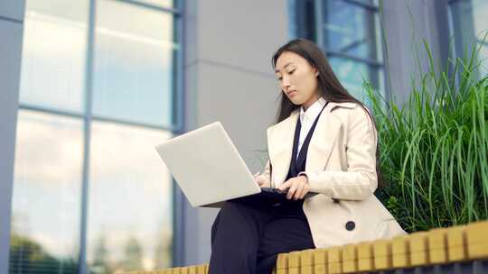 年轻的亚洲女商人远程工作，坐在现代办公室视频素材模板下载