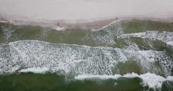 当海浪拍打海岸时，人们在海岸上行走