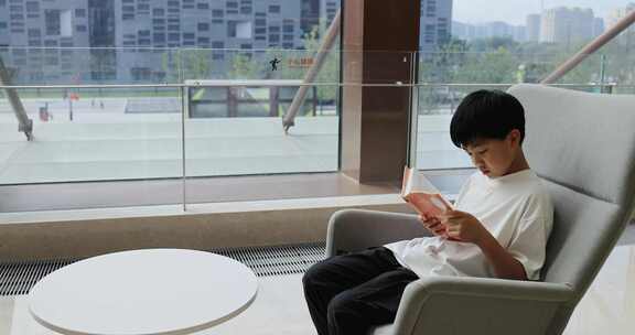 中国小男孩在图书馆大厅看书阅读