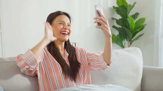 亚洲有魅力的女人在客厅使用手机视频通话。