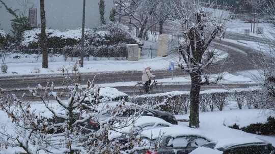 大雪天气路上行人吃力地骑着自行车