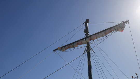 海盗船桅杆和卷起的帆站在晴朗的天空下，阳