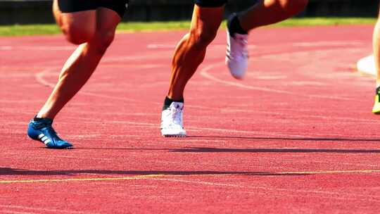 在跑道上比赛跑步的运动员腿部特写！