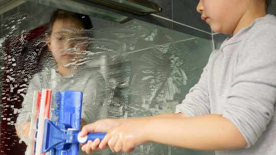 可爱的小女孩在家里擦玻璃做家务