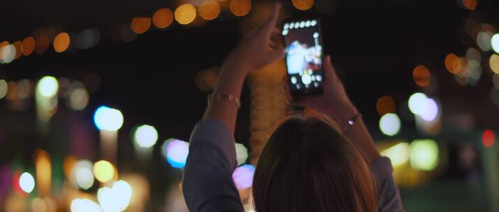 女人用手机拍摄城市夜景