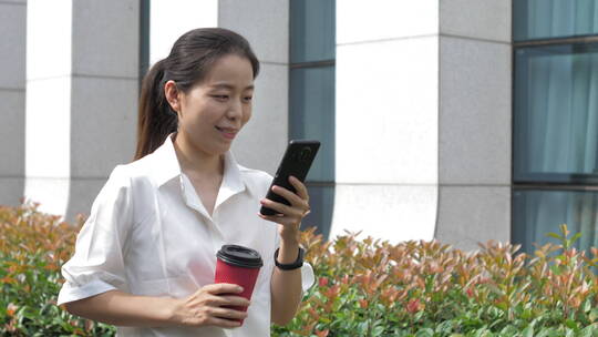 亚洲东方中国女性户外玩手机喝咖啡