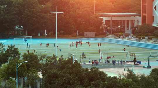 夕阳下学校足球场上踢球的儿童们