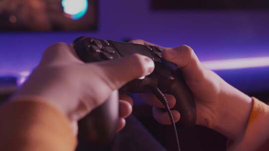 Detalle de mando y manos de青少年jugando a video ojuegos。
