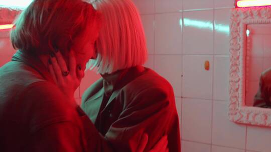 情侣在红色灯光的浴室里亲吻