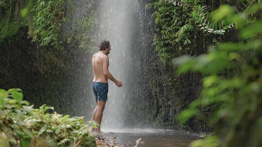 巴厘岛瀑布下的男子中景
