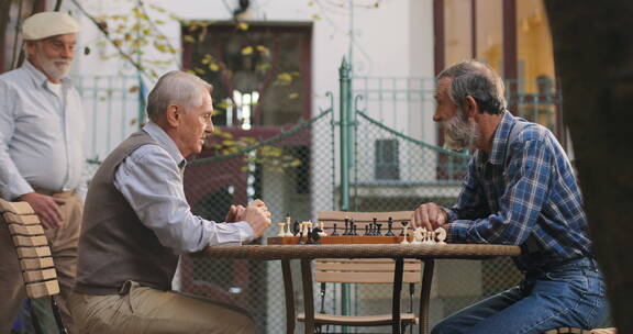 退休老人围着桌子下国际象棋 