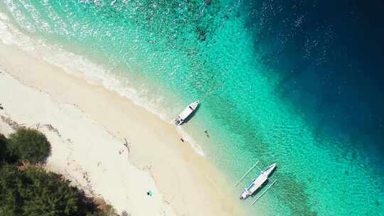 停泊在热带岛屿宁静海岸上的旅游船，宽阔的白色海滩被平静的c