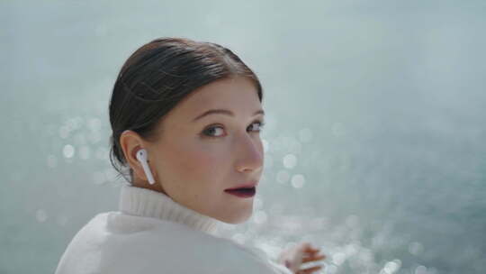 坐在湖水特写镜头前戴着无线耳塞听音乐的女游客