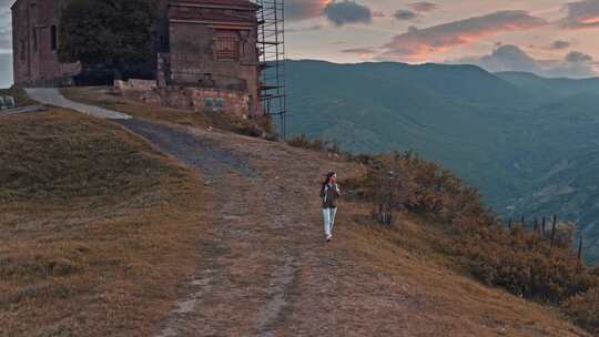 女人走在山间空中的小路上