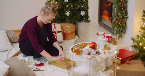 在家壁炉旁包装圣诞礼物的女人