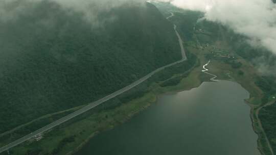 湖泊和道路上的山上有雾，汽车在空中行驶