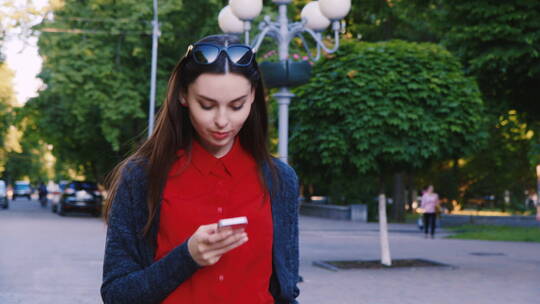 女人在街道上边走边玩手机视频素材模板下载