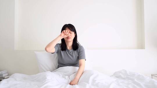 周末早晨年轻女孩起床坐在床上伸懒腰