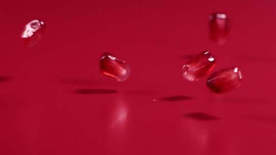 红石榴籽在红色背景中从空中落下，4k慢镜头