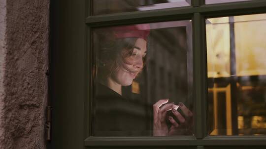 女人在窗口玩智能手机