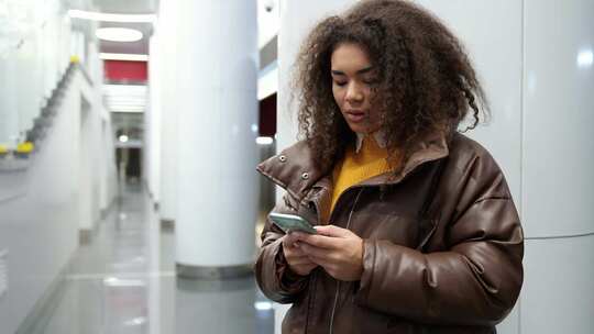 专注的非洲女性在地铁里等火车，用智能手机上网