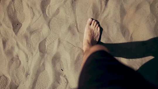 男子赤脚走在沙子上