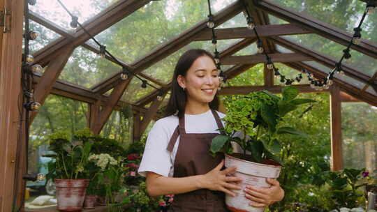 穿着工作服的女士看着盆栽植物的叶子