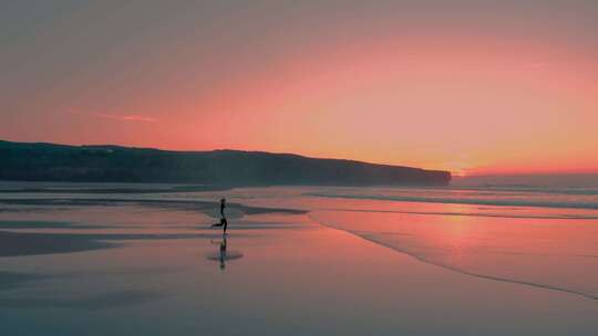 夕阳下女孩拿着冲浪板跑向大海