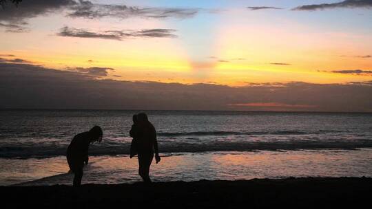 日落时海滩上的家庭剪影