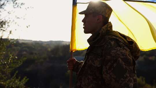 身着迷彩服的乌克兰陆军士兵举着蓝石旗帜站