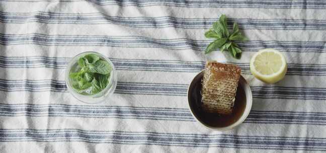 薄荷叶浸泡在带蜂窝的杯子旁边的杯子里