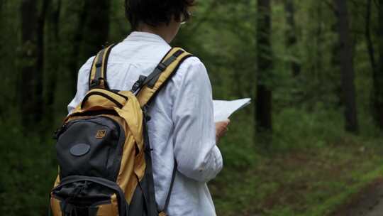 背着背包散步的年轻女子旅行者，看地图，徒