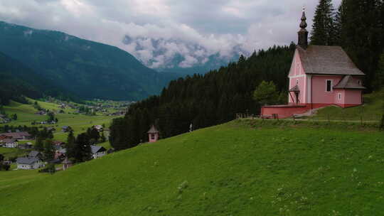 游客爬上台阶去山上的教堂。绿色山坡上的粉