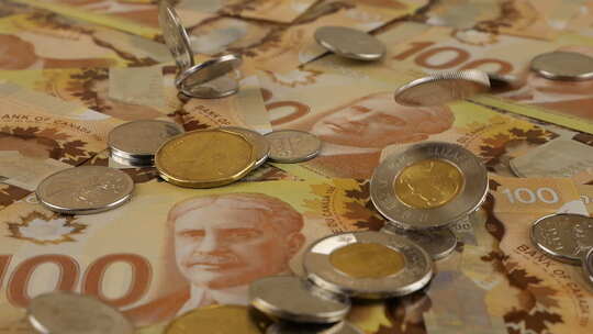 100美元聚合物纸币上掉落的加拿大硬币，上面有罗伯特·博登的肖像。慢动作