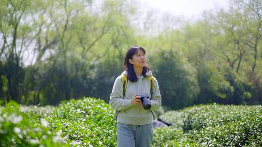 春天年轻女孩郊游茶园手拿相机拍摄美丽景色