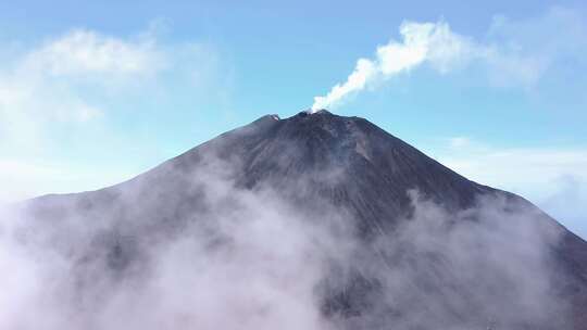 蓝天下，云层在火山周围移动
