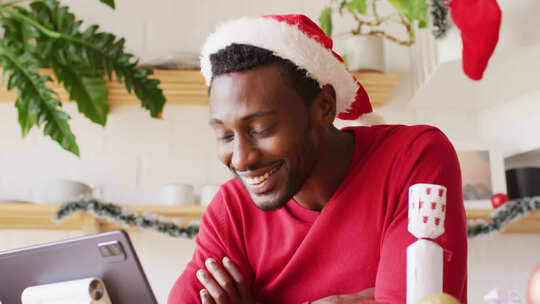 快乐的非裔美国人戴着圣诞帽，使用平板电脑进行视频通话
