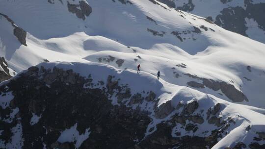 航拍在雪山山脊上行走的登山者