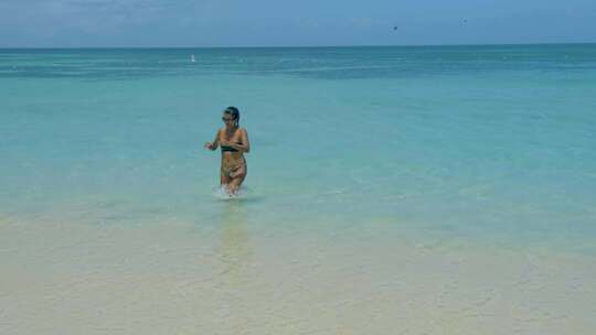 在海滩上放松的女人棕榈滩阿鲁巴岛加勒比海白色长沙海滩与棕榈树在