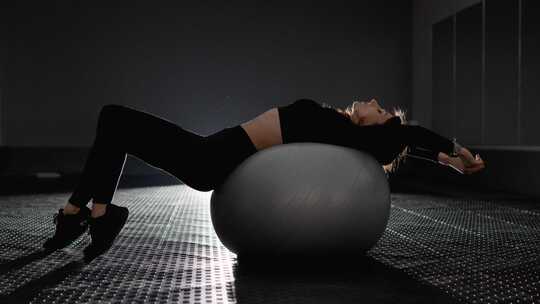 女人小心翼翼地使用健身球进行各种锻炼来加