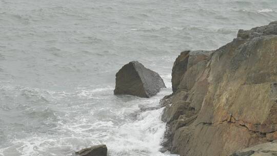 海边浪花拍打礁石，沙滩