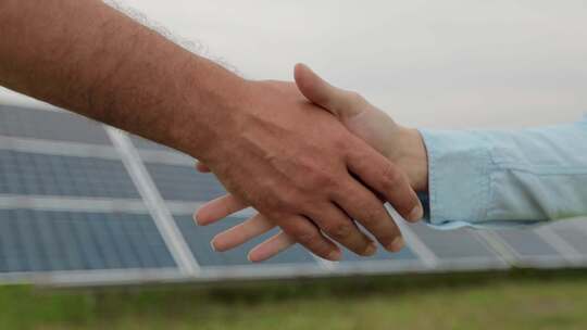 在光伏基地前两个人握手绿色能源概念